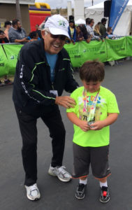 Admiring his well-deserved medal, this young boy (and all the other runners) should be proud. This one-mile race concluded a 10-week program during which runners completed 26.2 miles (a full marathon). May 6, 2017. Costa Mesa, Calif. Photo: F. Rehnborg