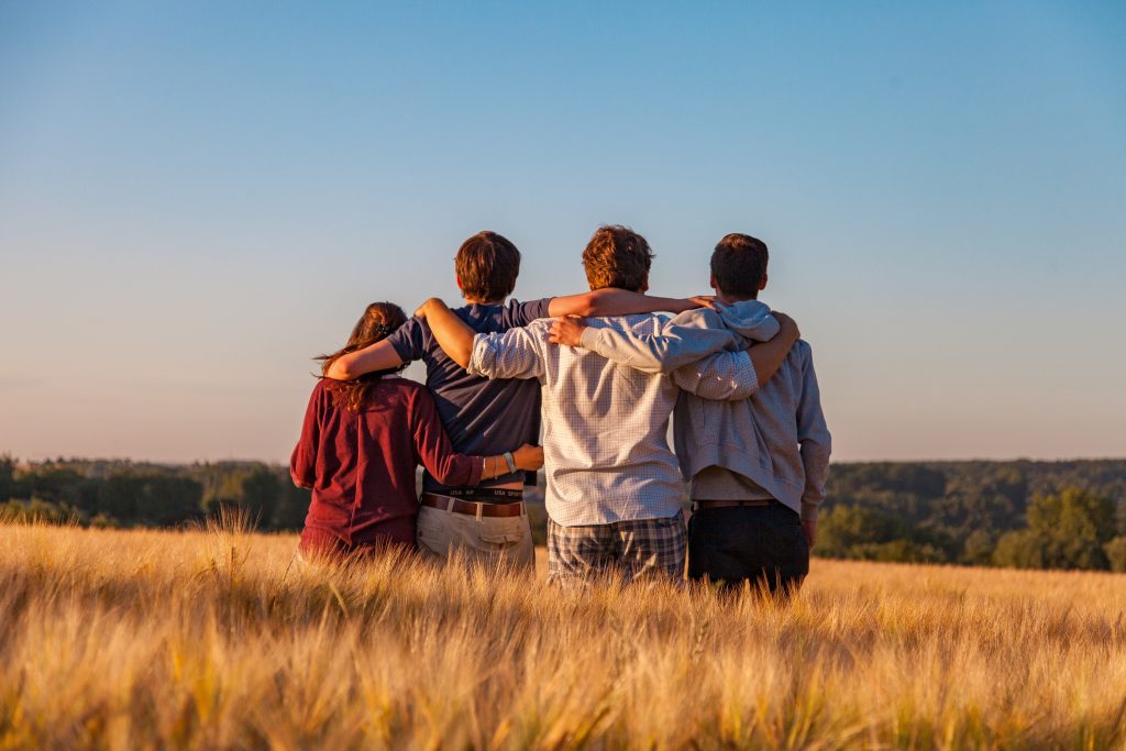 Four people embrace in a grassy field as they look to the horizon. Rare diseases affect an estimated 1 in 20 people and most likely include people you know. Photo Credit: Dimitri Houtteman