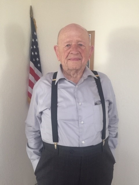 Don Hitzel stands in front of an American flag. Celebrating his 100th birthday, Don is a perfect example of being 100 years YOUNG.