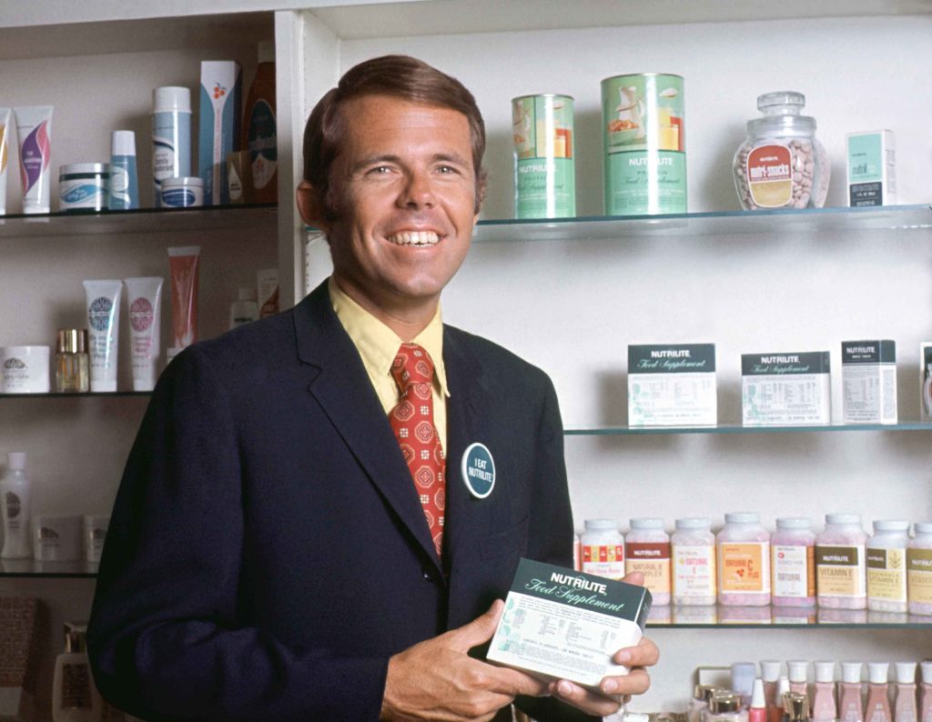 Holding a container of Nutrilite™ food supplement. If you look closely you can see the “I Eat Nutrilite” button on my jacket lapel as a reminder to customers that Double X is something you “eat” to fill nutrient gaps to maintain good health rather than a pill that you “take” to treat disease.