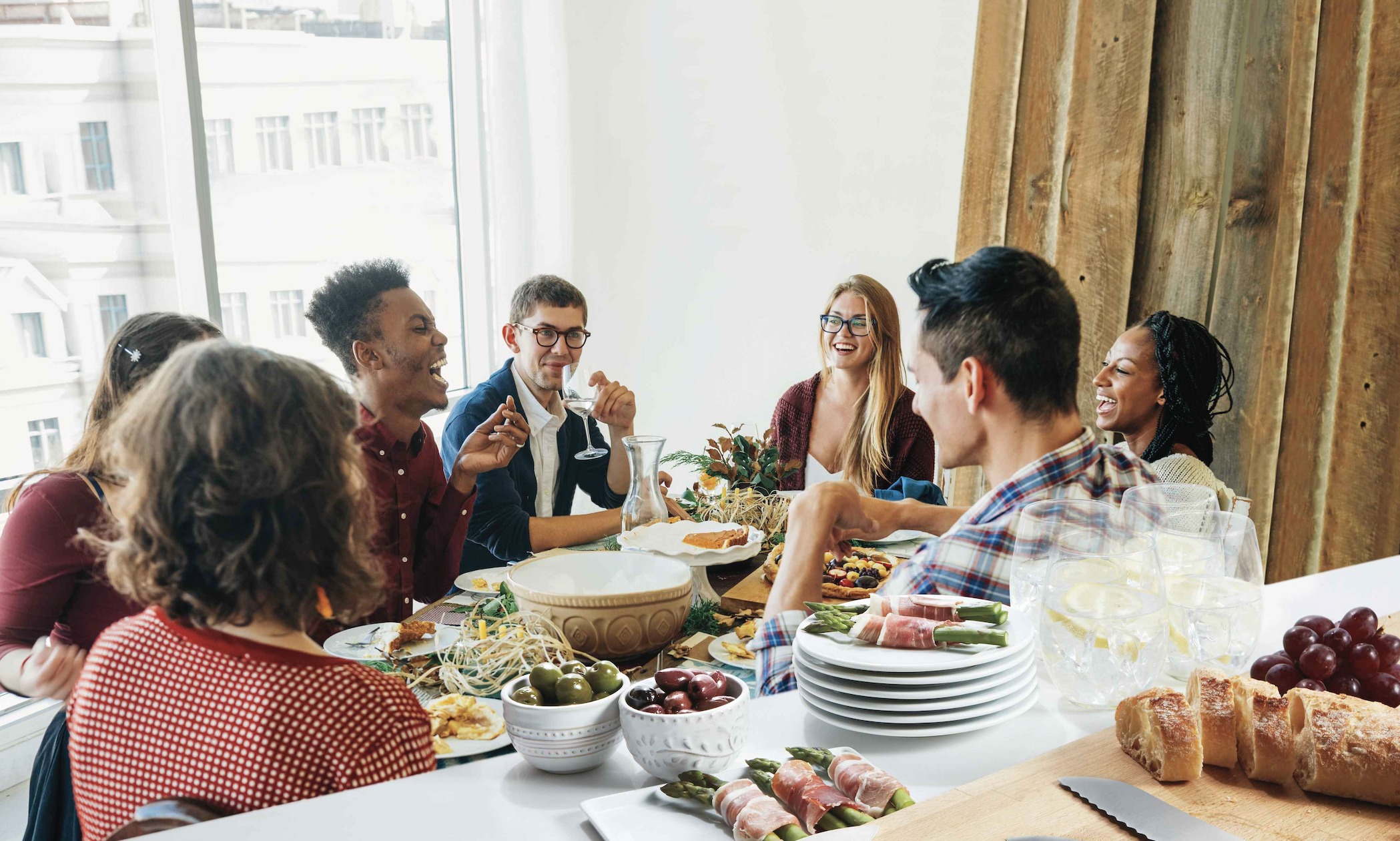 Friends gather together around a dining table for a feast. Being together with people you care for is about one of the best medicines for the mind, body and spirit.